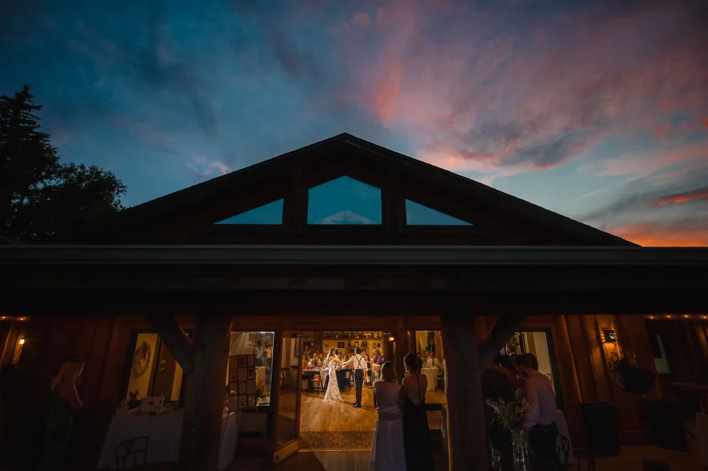 Bride and groom dance as guest look on during sunset.