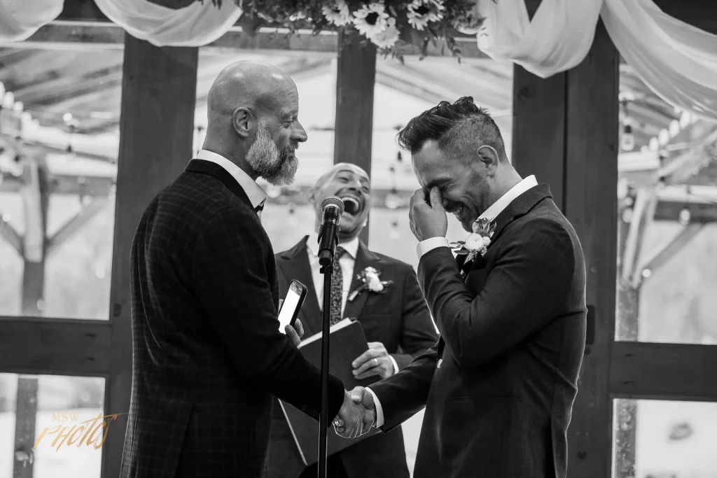Two grooms and their officiant laugh during their colorado wedding ceremony.