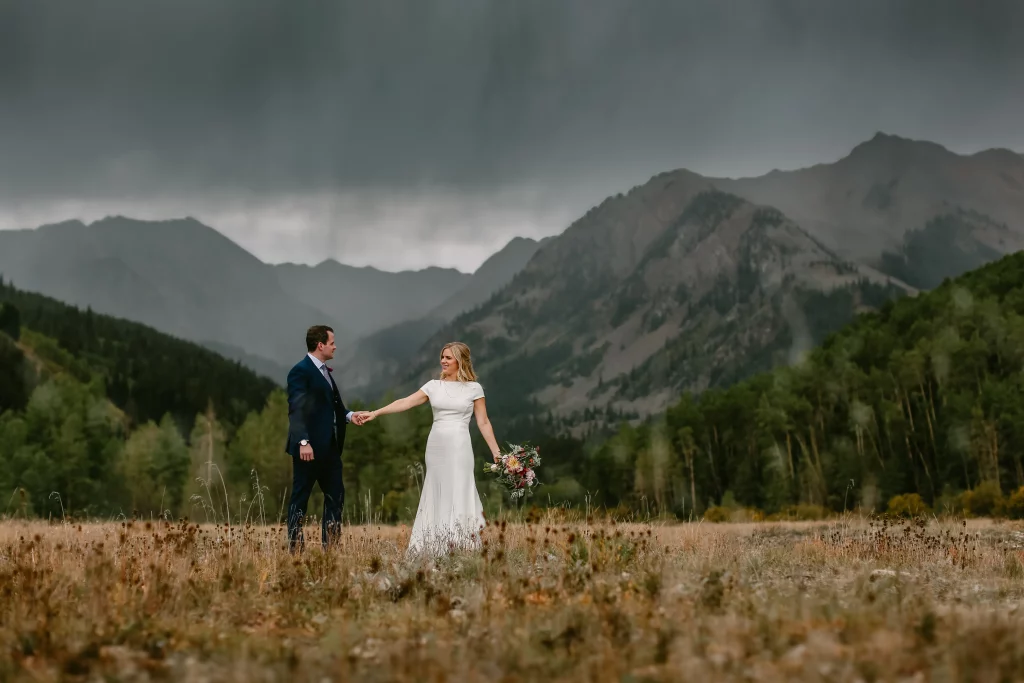 A bride and groom strolling through an mountain meadow in Aspen, CO.